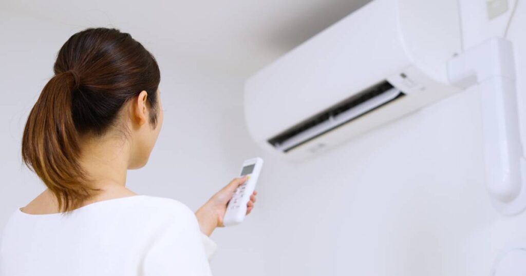 Femme réglant la température intérieur avec un climatiseur réversible